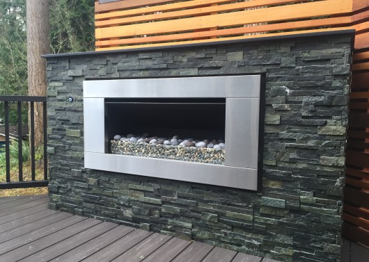 Fireplace with stone veneer, Dekton countertop, and stainless fireplace insert